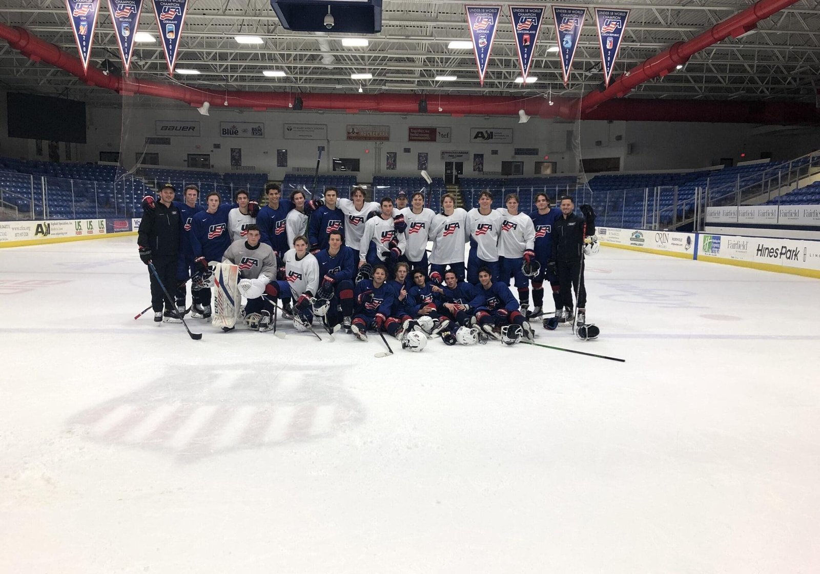 Players and coaches on the ice at USA Hockey Arena